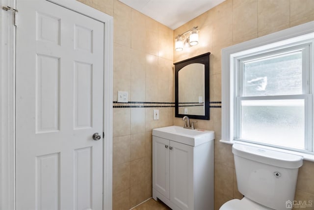 half bathroom with toilet, tile walls, and vanity
