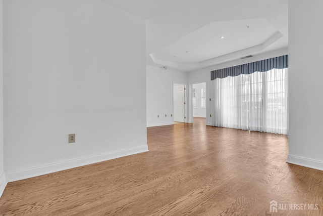 empty room featuring hardwood / wood-style floors and a tray ceiling