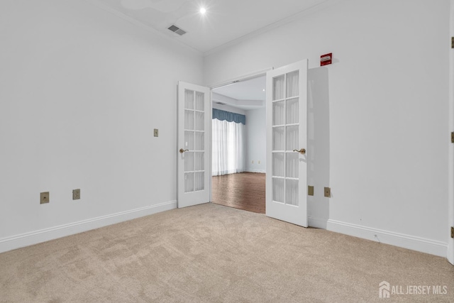 empty room with ornamental molding, light colored carpet, and french doors