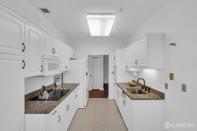 kitchen with white cabinetry, sink, white appliances, and dark stone countertops