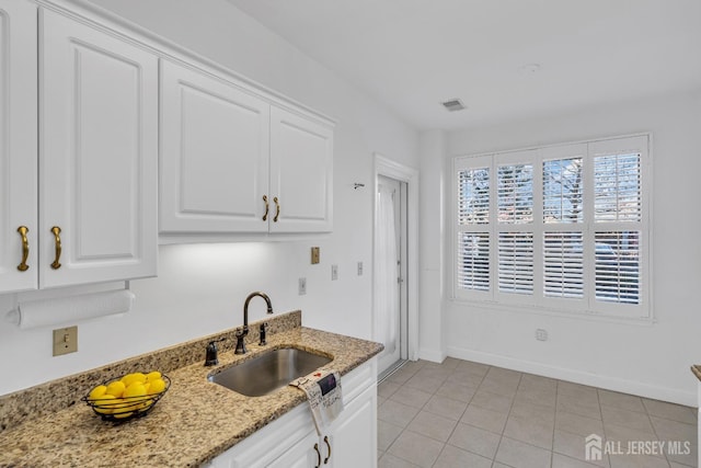 kitchen with white cabinetry, light stone countertops, sink, and light tile patterned floors