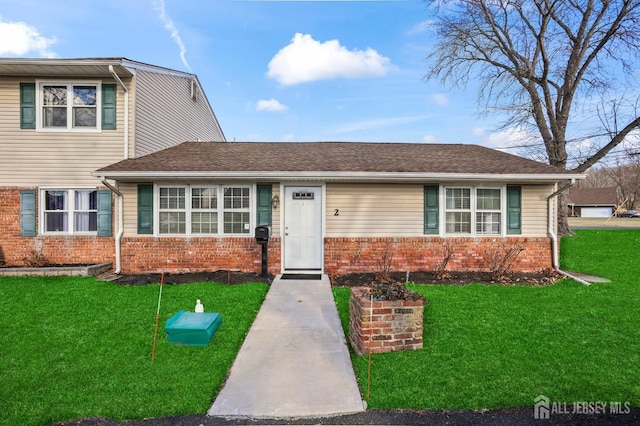 view of front of home with brick siding, a front yard, and a shingled roof