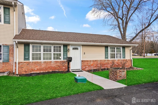 single story home featuring brick siding, roof with shingles, and a front yard