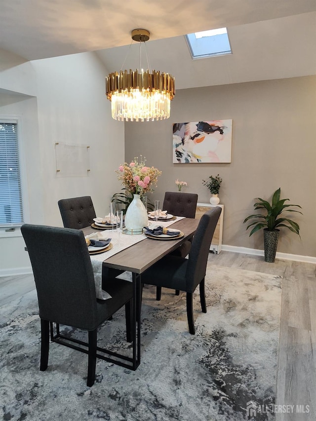 dining area featuring hardwood / wood-style floors, lofted ceiling with skylight, and a notable chandelier