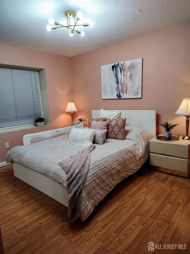 bedroom with hardwood / wood-style floors and an inviting chandelier