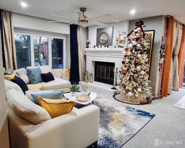 carpeted living room with ceiling fan, a fireplace, and brick wall