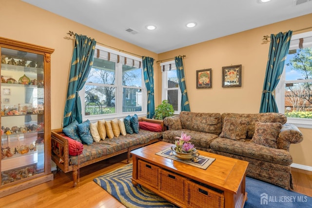 living area with recessed lighting, visible vents, and wood finished floors