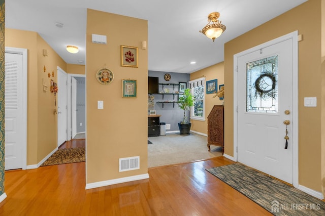 foyer featuring visible vents, baseboards, and wood finished floors
