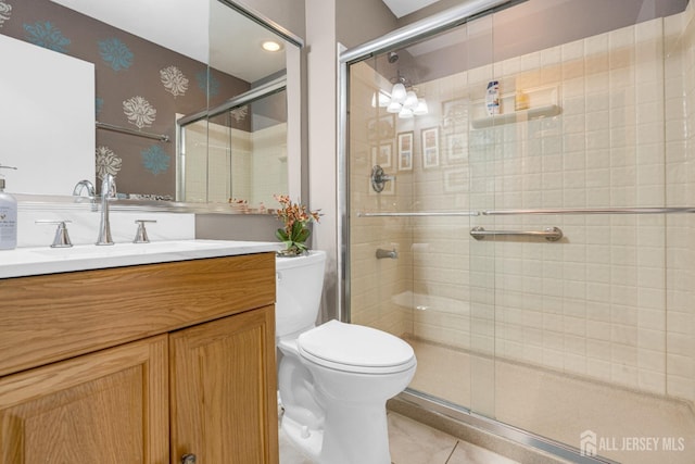 bathroom featuring tile patterned flooring, a stall shower, vanity, toilet, and wallpapered walls