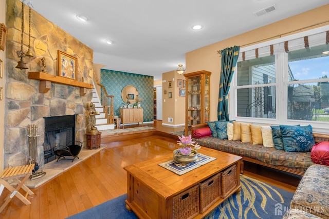 living area featuring visible vents, stairs, an accent wall, and hardwood / wood-style flooring