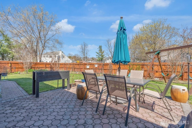 view of patio / terrace with outdoor dining area, a fenced backyard, and a playground