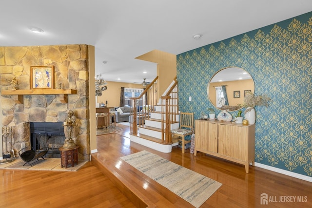 stairway with wood finished floors, an accent wall, baseboards, wallpapered walls, and plenty of natural light