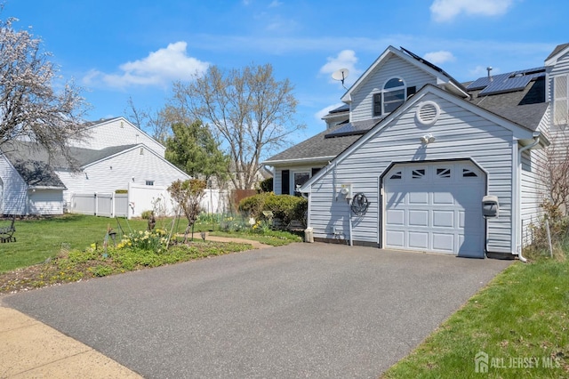 view of front of house with a garage, aphalt driveway, fence, a front yard, and a shingled roof