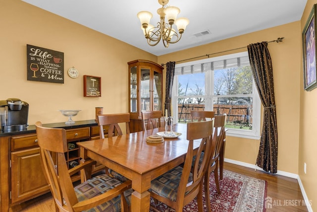 dining space featuring light wood-style floors, baseboards, visible vents, and a notable chandelier