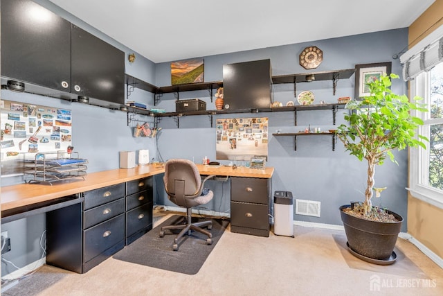 carpeted office with baseboards, visible vents, a wealth of natural light, and built in study area