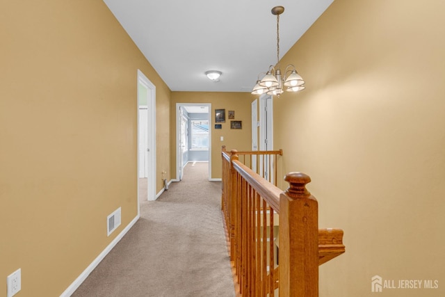 corridor featuring visible vents, an upstairs landing, baseboards, a notable chandelier, and carpet