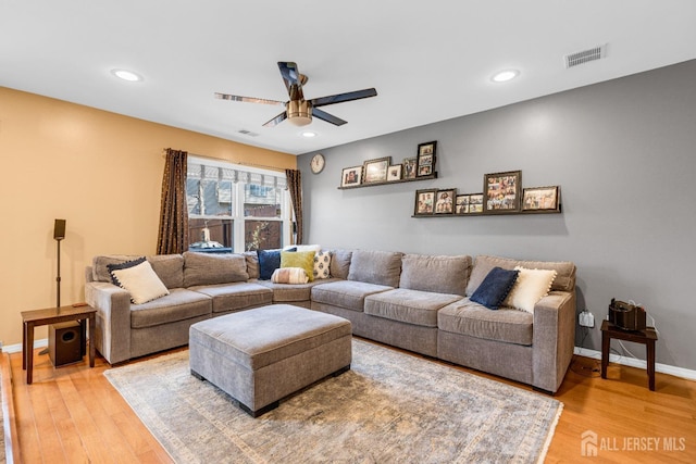 living area featuring baseboards, ceiling fan, light wood finished floors, and visible vents