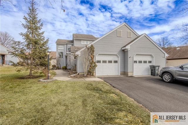 view of front of house featuring an attached garage, aphalt driveway, and a front yard