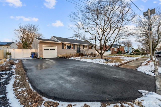 single story home featuring a garage, a chimney, fence, and aphalt driveway