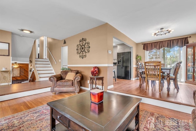 living room featuring light wood-style floors, stairs, and baseboards