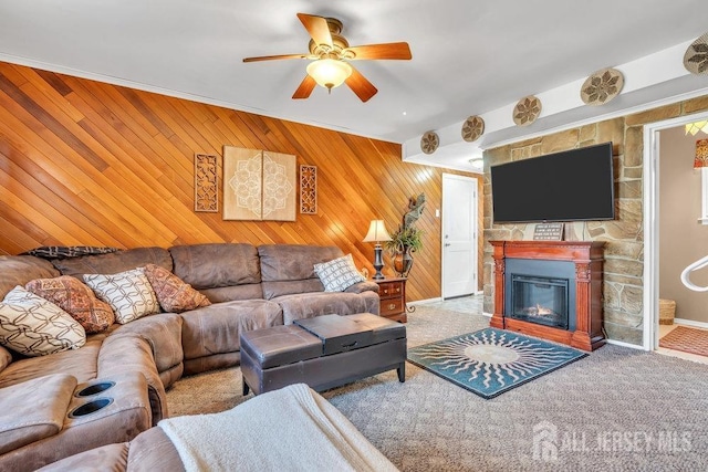 carpeted living area with a fireplace, a ceiling fan, and wood walls