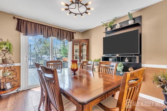 dining area with baseboards, an inviting chandelier, and light wood finished floors