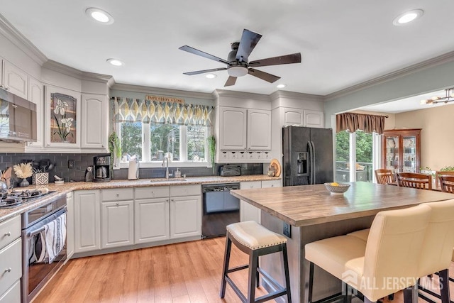 kitchen featuring a sink, plenty of natural light, black appliances, and a kitchen bar