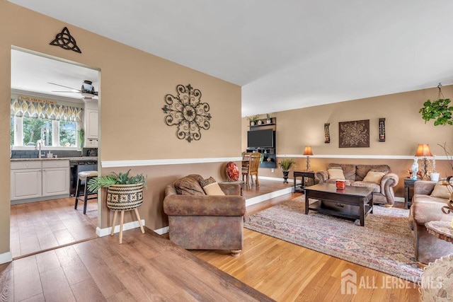 living area with light wood-type flooring, a ceiling fan, and baseboards
