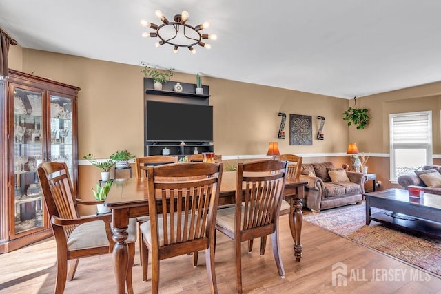 dining area with light wood-style flooring and a notable chandelier