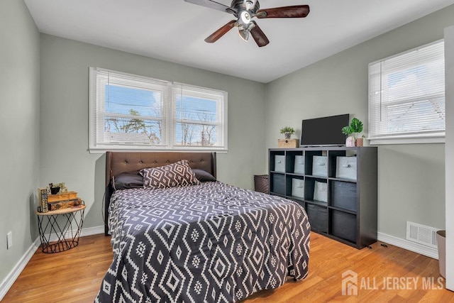bedroom with baseboards, wood finished floors, and visible vents