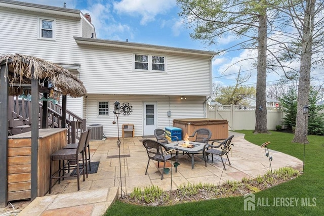 back of house featuring fence private yard, a patio area, outdoor dry bar, a hot tub, and central air condition unit