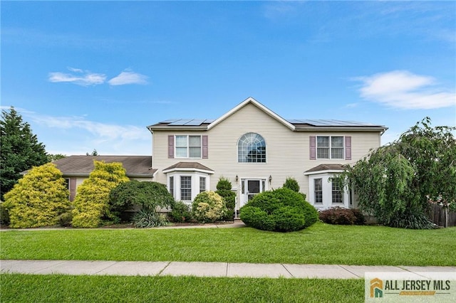 254 Wyoming Ave, Spotswood, NJ 08884 - colonial-style house featuring a front yard and roof mounted solar panels