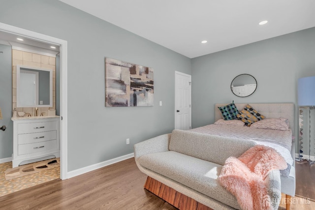 bedroom with baseboards, wood finished floors, recessed lighting, and a sink