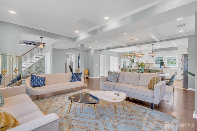 living room featuring a chandelier, wood finished floors, stairs, baseboards, and crown molding