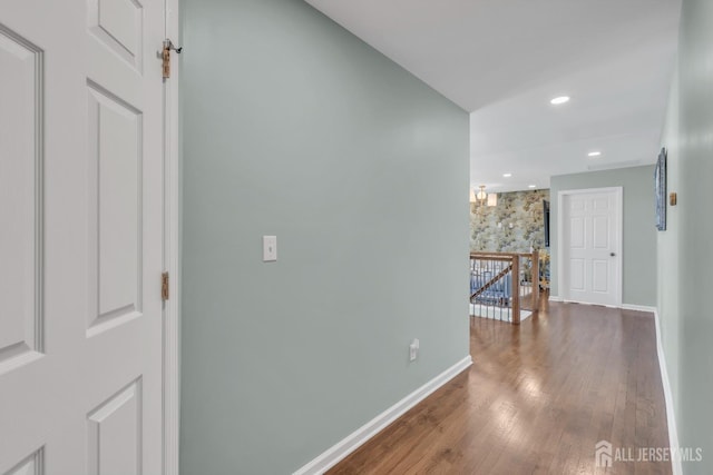 corridor with an upstairs landing, baseboards, wood finished floors, and recessed lighting