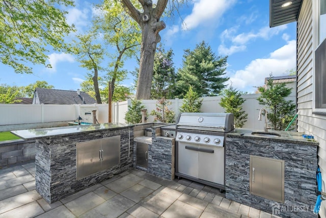 view of patio / terrace featuring area for grilling, a sink, a fenced backyard, and grilling area
