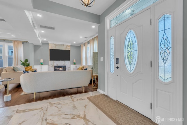 entrance foyer with recessed lighting, a premium fireplace, marble finish floors, and baseboards