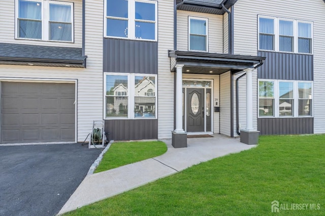 view of front of property featuring a garage, a front lawn, asphalt driveway, and board and batten siding