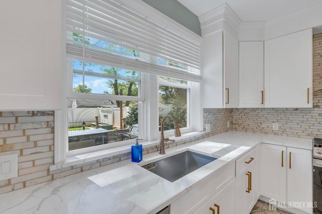kitchen featuring a sink, white cabinets, light stone countertops, and plenty of natural light