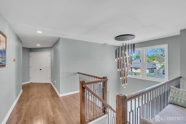 corridor featuring an upstairs landing, wood finished floors, baseboards, and recessed lighting