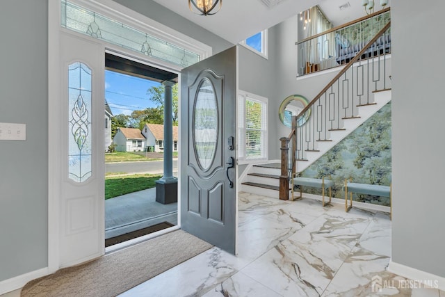foyer entrance with plenty of natural light, baseboards, and a towering ceiling