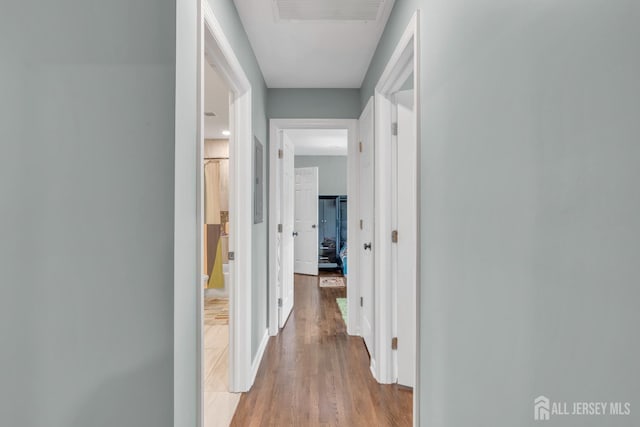 corridor featuring light wood finished floors and baseboards