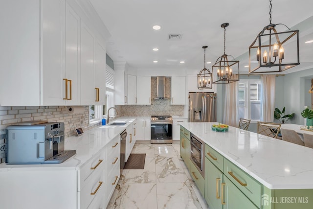kitchen featuring stainless steel appliances, a chandelier, wall chimney exhaust hood, a spacious island, and white cabinets