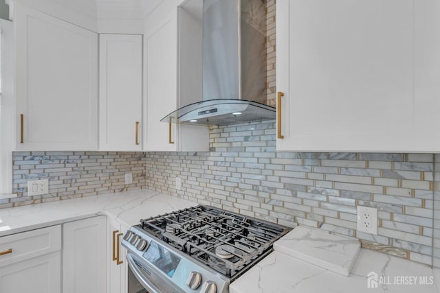 kitchen with wall chimney range hood, gas range, white cabinets, and light stone countertops