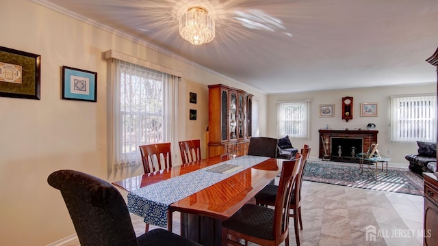 dining area featuring a fireplace, an inviting chandelier, and ornamental molding