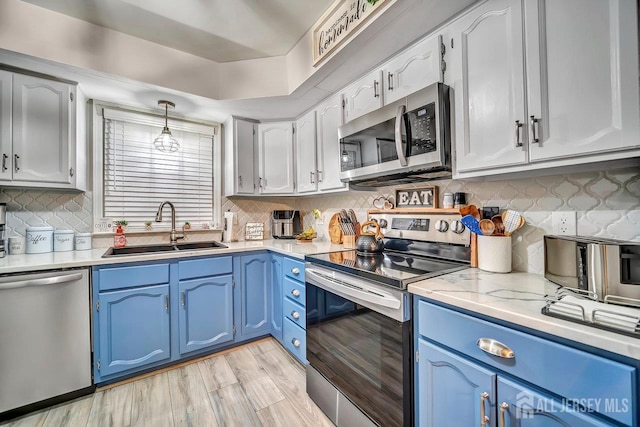 122 Concordia Cir Unit B, Monroe, NJ 08831 - kitchen featuring stainless steel appliances, blue cabinets, decorative backsplash, light wood-style flooring, and hanging light fixtures