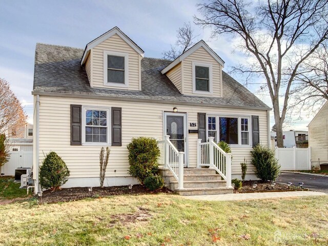 cape cod-style house with central AC unit and a front lawn