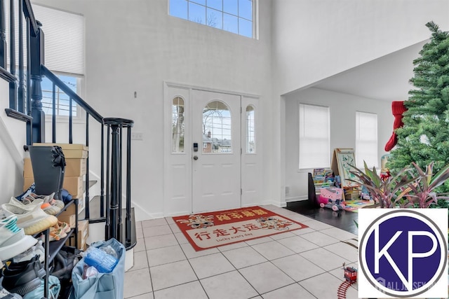 tiled entrance foyer with stairway, baseboards, and a high ceiling