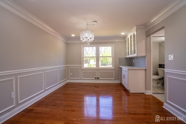 4 Harvey Rd, South Brunswick, NJ 08852 - unfurnished dining area with a chandelier, crown molding, a decorative wall, wood finished floors, and wainscoting
