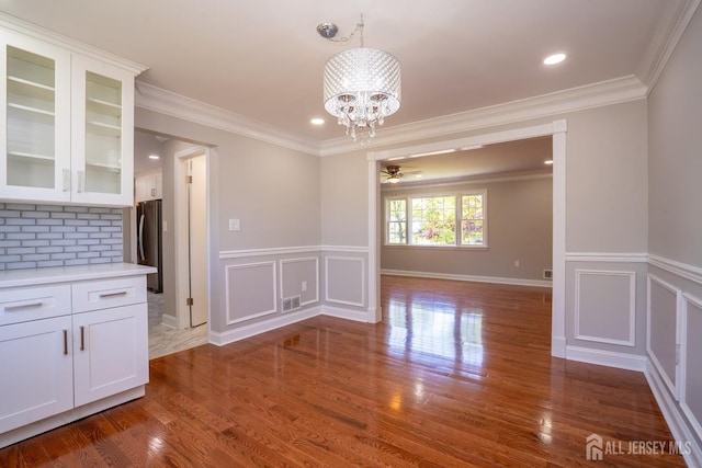 4 Harvey Rd, South Brunswick, NJ 08852 - unfurnished dining area featuring a chandelier, ornamental molding, a decorative wall, wood finished floors, and wainscoting